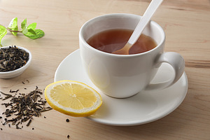 Tea with lemon in white ceramic cup on wooden table, a Food & Drink Photo by Davizro's Market