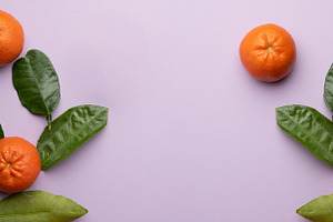 Ripe tangerines and green leaves on a purple background,, a Food & Drink Photo by ndanko
