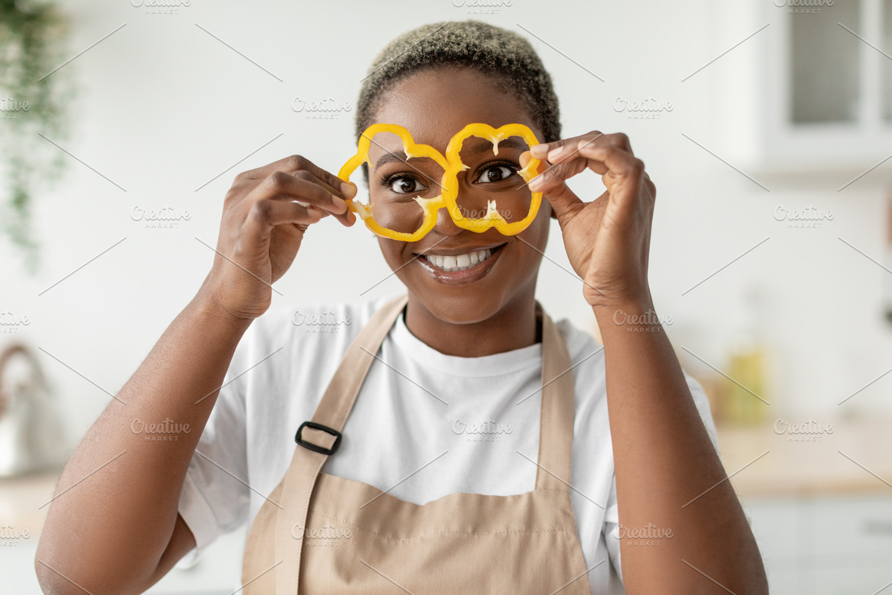 Happy millennial african american lady housewife in apron have fun and puts pie, a Person Photo by Prostock-Studio