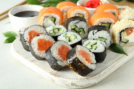 Concept of tasty food with sushi rolls on white textured backgro, a Food & Drink Photo by AtlasStudio