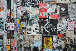 A vibrant urban wall covered with a collage of posters, graffiti, and street ar, a Background Graphic by Textures & Backgrounds
