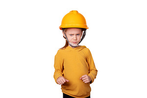 Young child in yellow safety helmet and sweater stands with a co, a Person Photo by Ales Munt