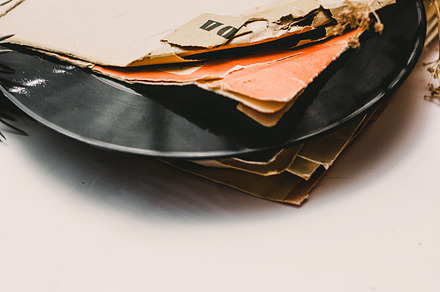 Stack of scratched dusty old vinyl records tied with rope on white background