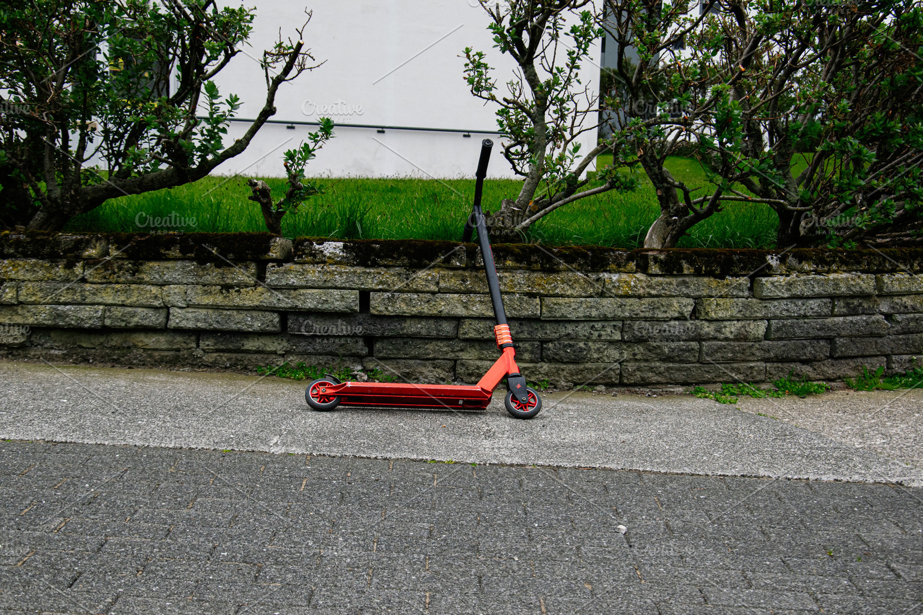 Red scooter resting near a stone wall in Reykjavik, Iceland, a Photo by AS photostudio