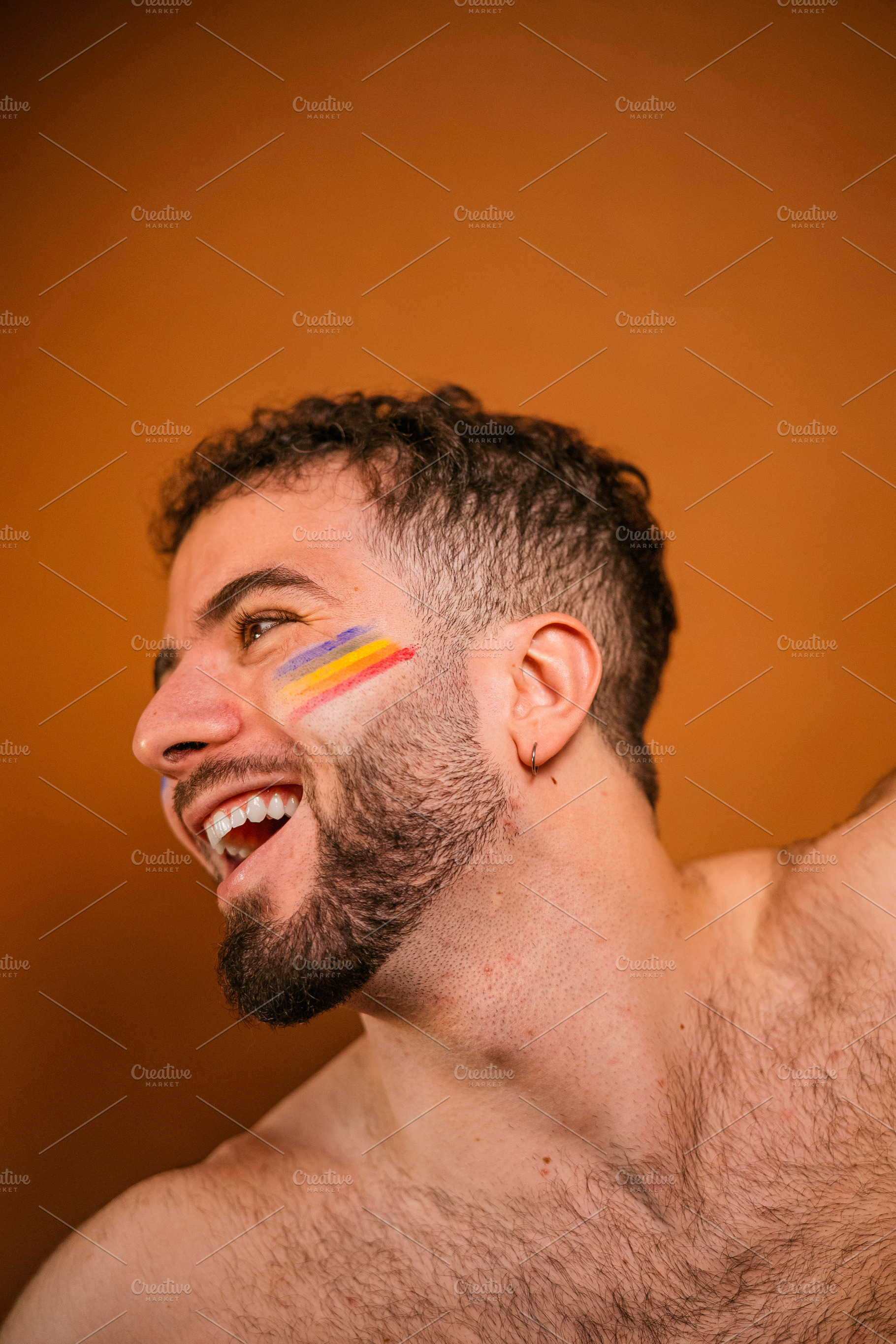 Happy man celebrating pride with rainbow face paint, a Photo by karrastock