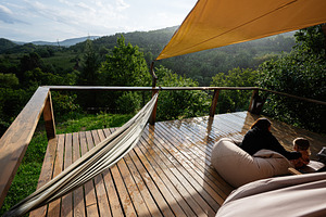 Relaxing wooden patio overlooking lush green forest and misty mountain views, a Photo by AS photostudio