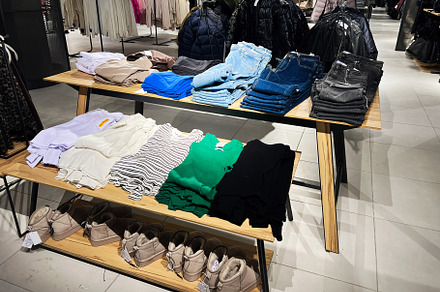 Folded clothes and footwear arranged on display in a retail clothing store, a Photo by AS photostudio