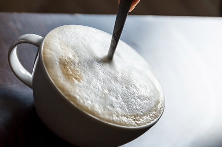 Cup of coffee with foam being stirre, a Food & Drink Photo by TanaCh