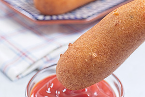 Corn dog with ketchup, vertical, a Food & Drink Photo by iuliia_n
