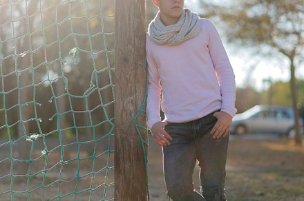Portrait of a teenager leaning against a park flagpole, looking away, a Person Photo by RF Images