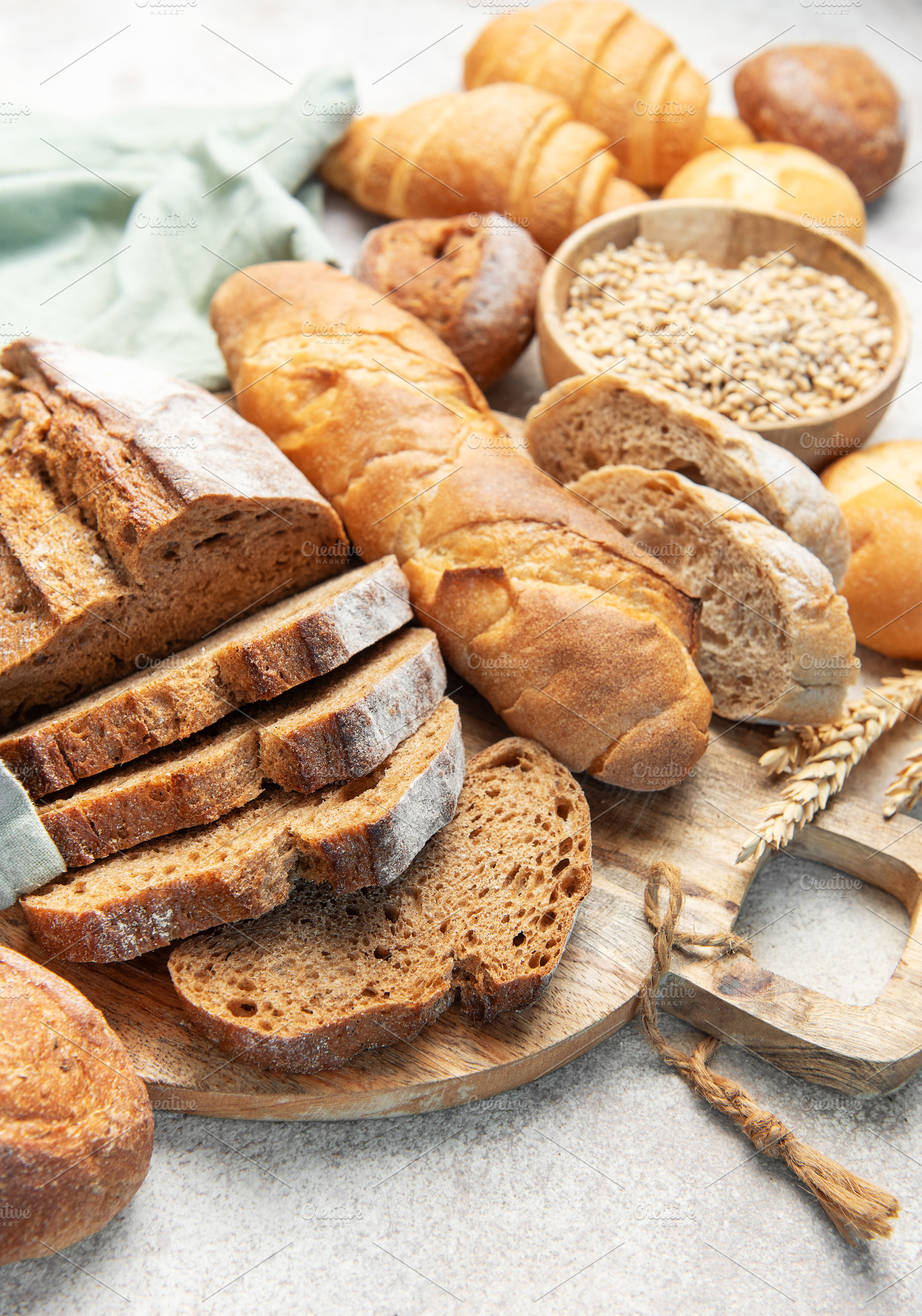 Assorted fresh bread, baguette, and croissants on cutting board, a Food & Drink Photo by Olena Rudo