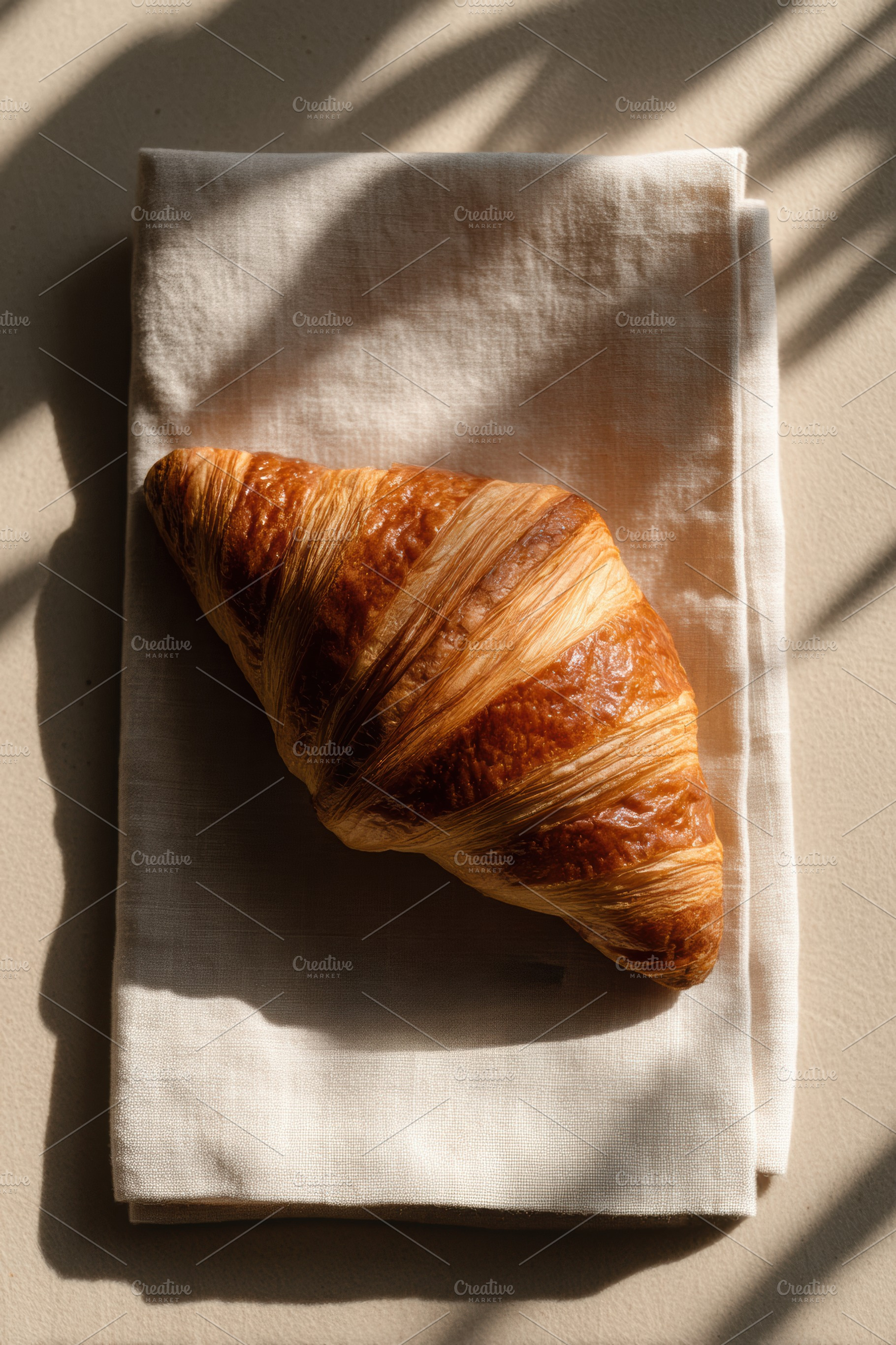 Single croissant on linen napkin, a Food & Drink Photo by Virgo Studio