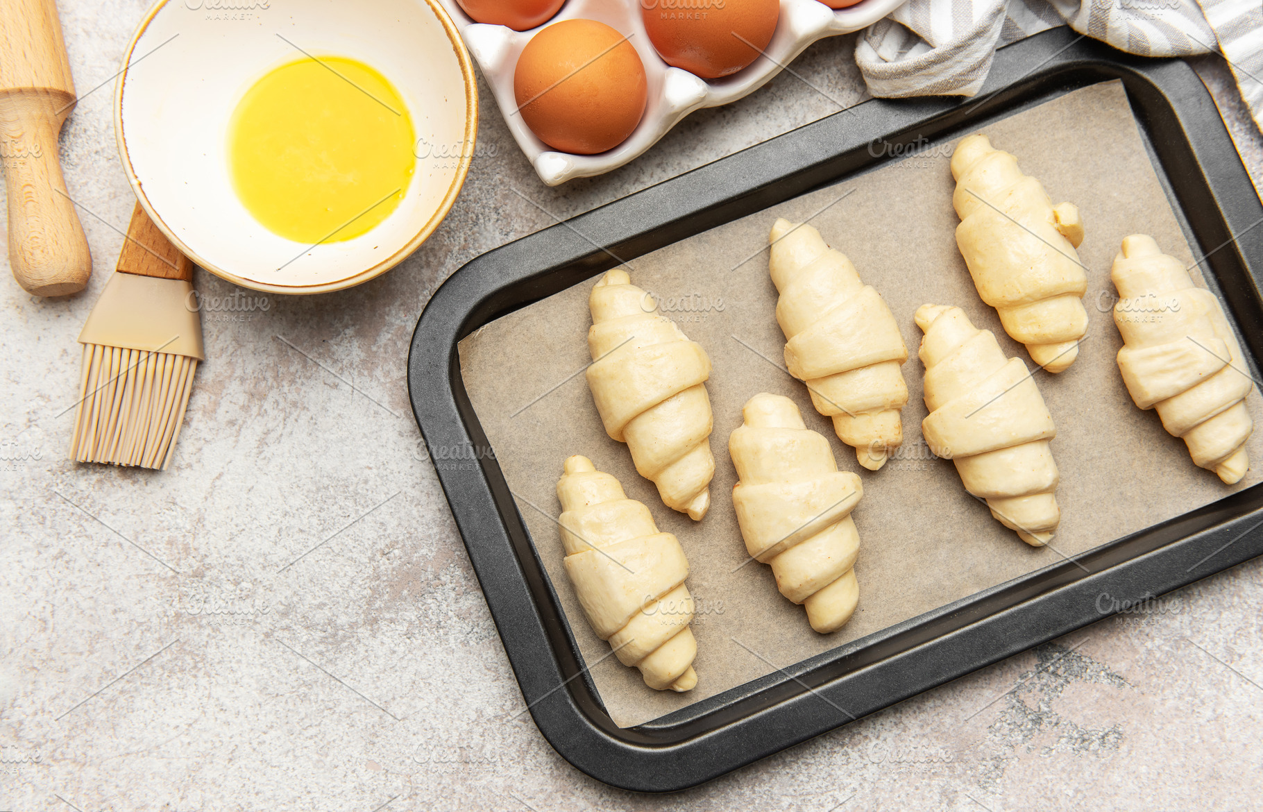 Baker preparing raw croissants on baking tray for baking, a Food & Drink Photo by Olena Rudo