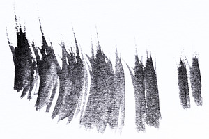 Abstract black brush strokes and paint dashes on textured white