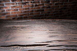 Old wooden empty table and brick wall in the background., a Background Photo by Volff
