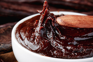 a spoon lifts carob cream from a white bowl, a Photo by Nito