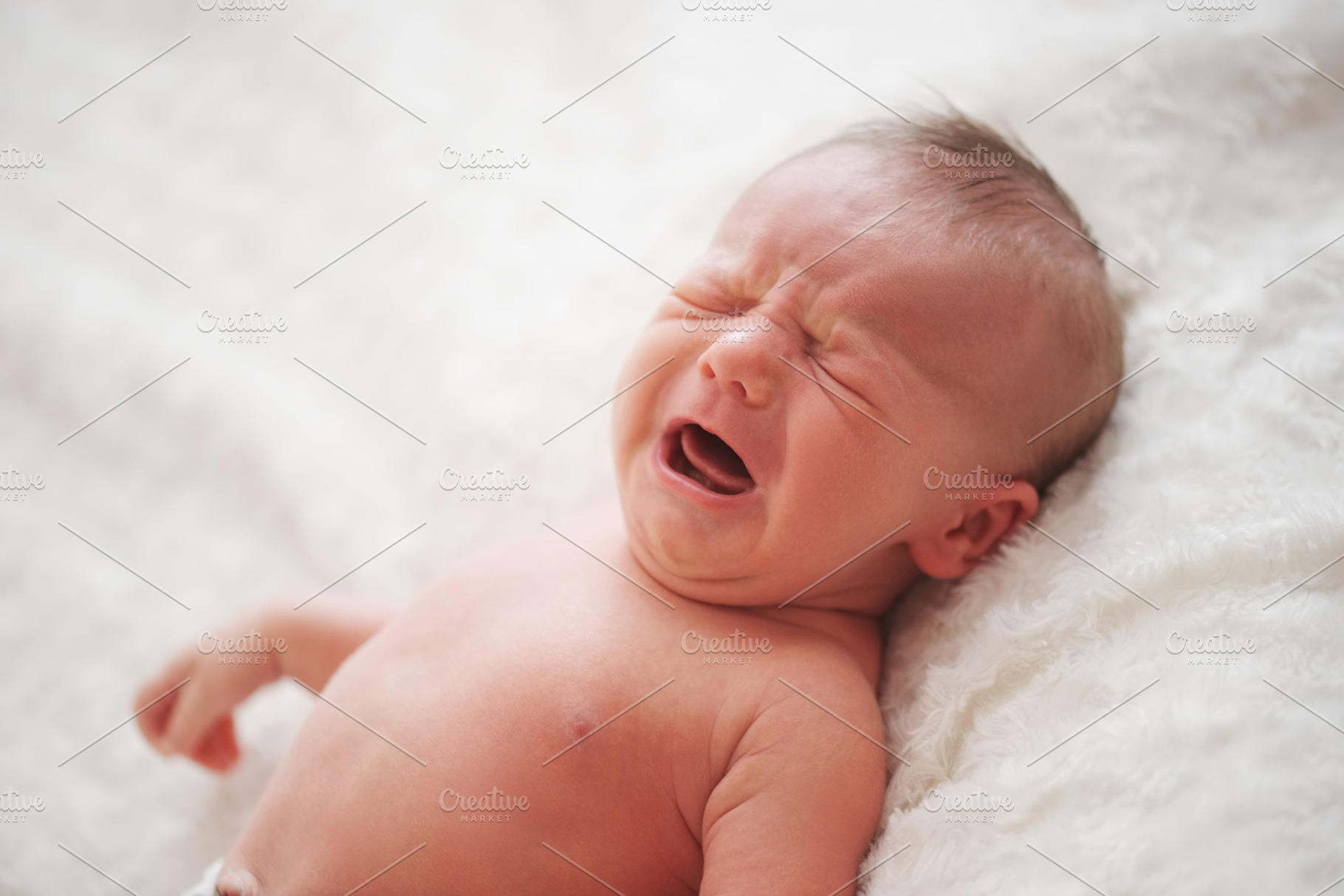 Cute crying newborn baby at home stock photo containing baby and portrait, a Beauty & Fashion Photo by AlohaHawaii