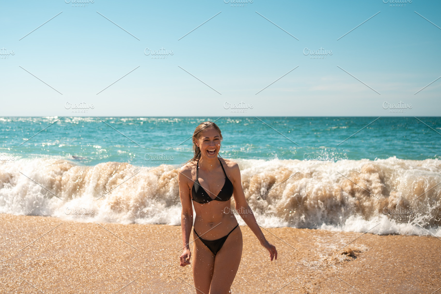 Cheerful sensuous woman in black bikini walking on seashore at beach, a Person Photo by andreonegin market