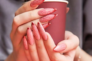 Woman holding insulated cup with long red ombre manicure, a Beauty & Fashion Photo by Olena Rudo