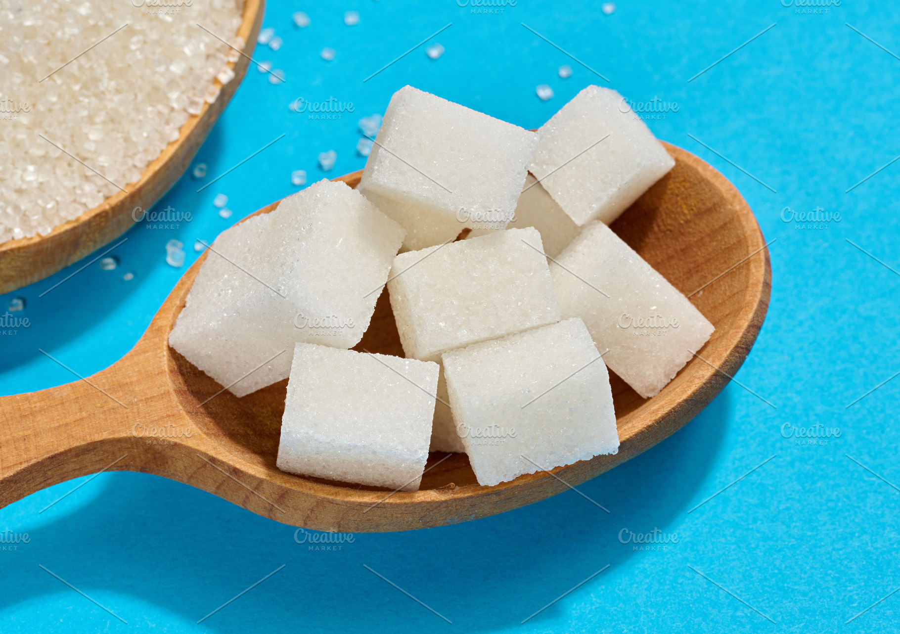 Wooden spoon filled with pieces of white refined sugar, blue bac, a Food & Drink Photo by ndanko