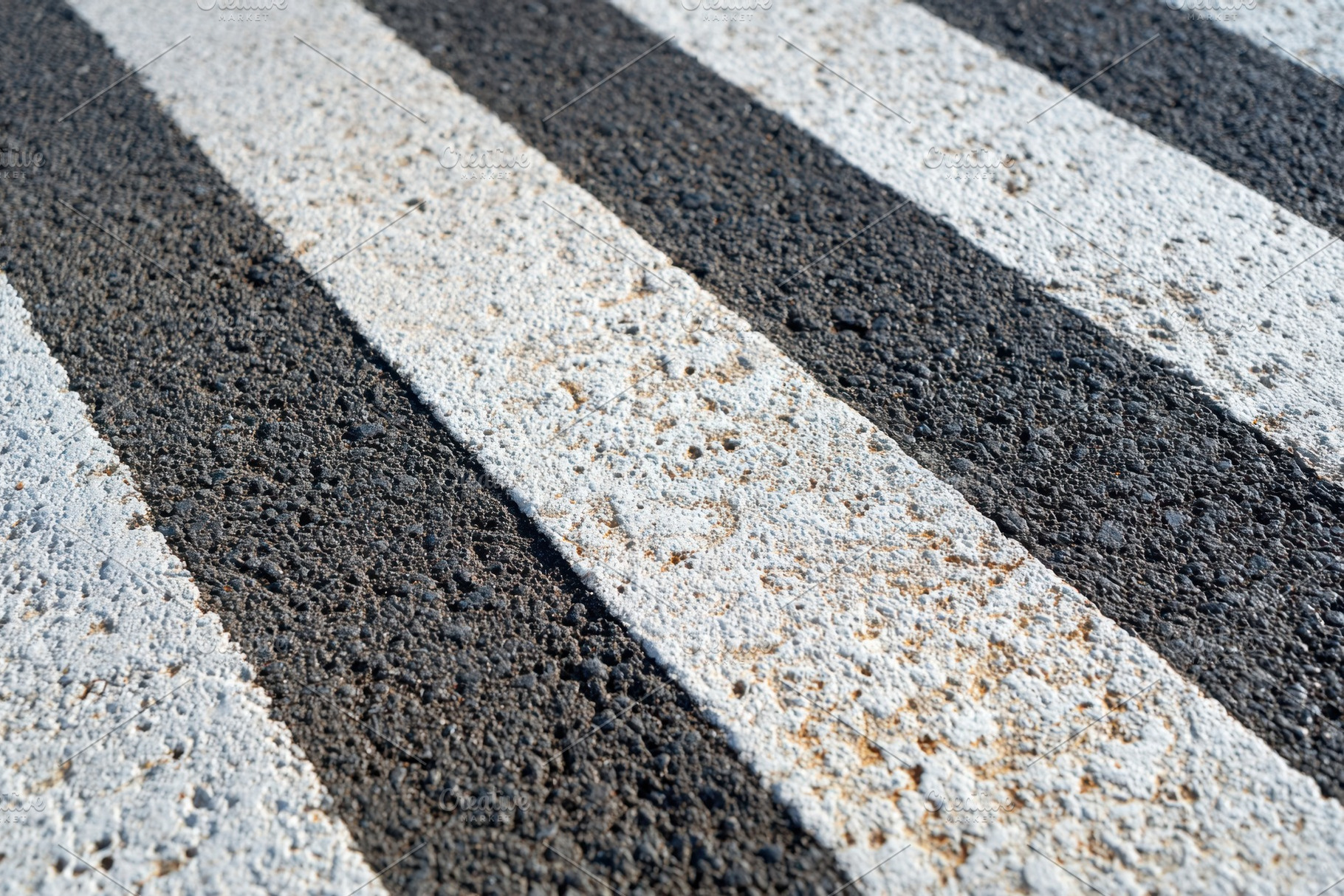 Textured asphalt surface with black and white stripes, an Abstract Photo by AlyaAnd