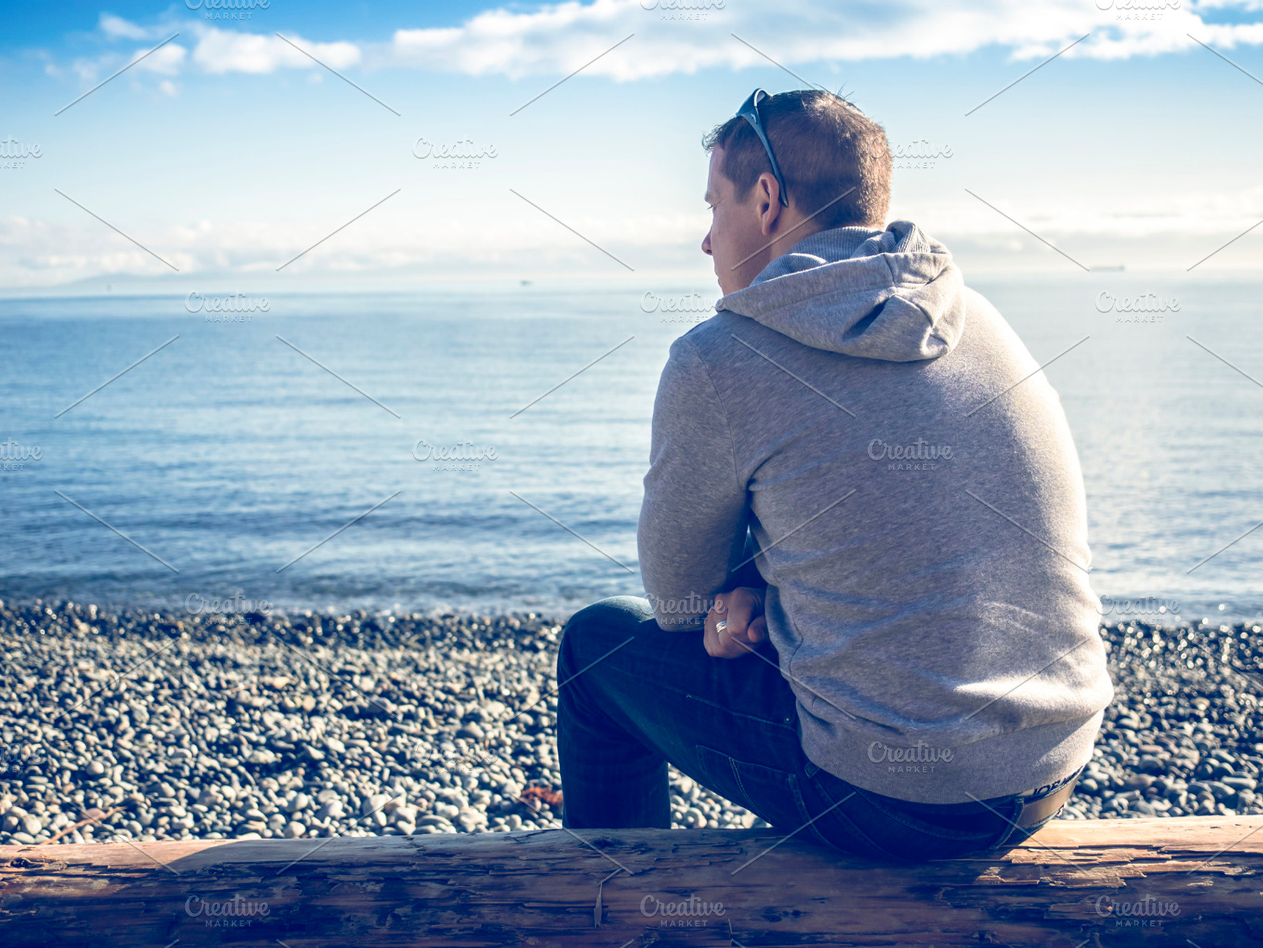 Man sitting looking out at ocean, a Person Photo by Imagefountain Photos