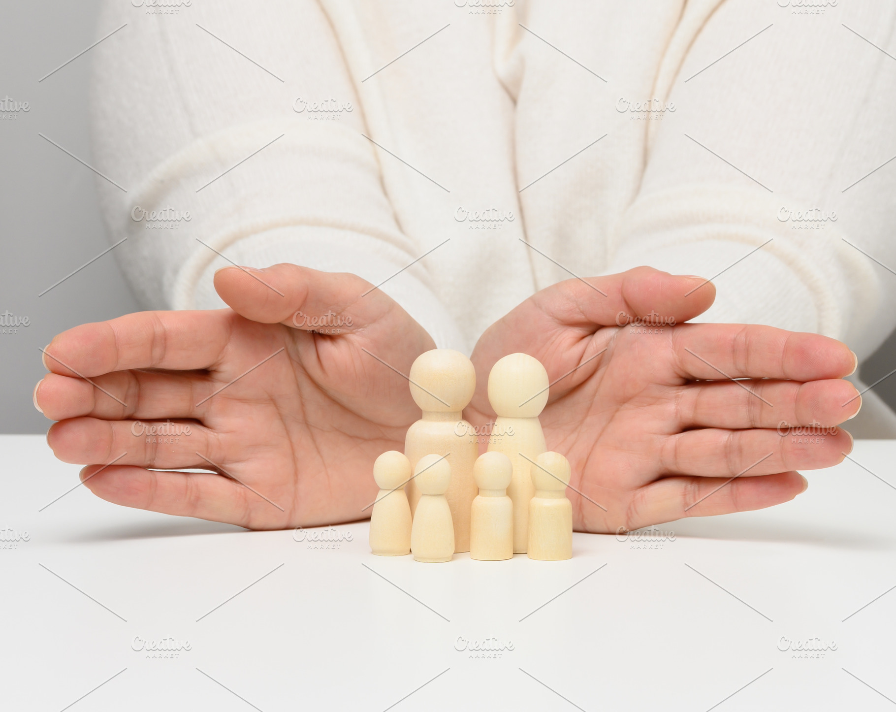 Female hands protect wooden figures of a family of parents and t, a Person Photo by ndanko