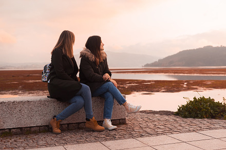 Two female friends sitting on a bench, a Person Photo by rubenchase