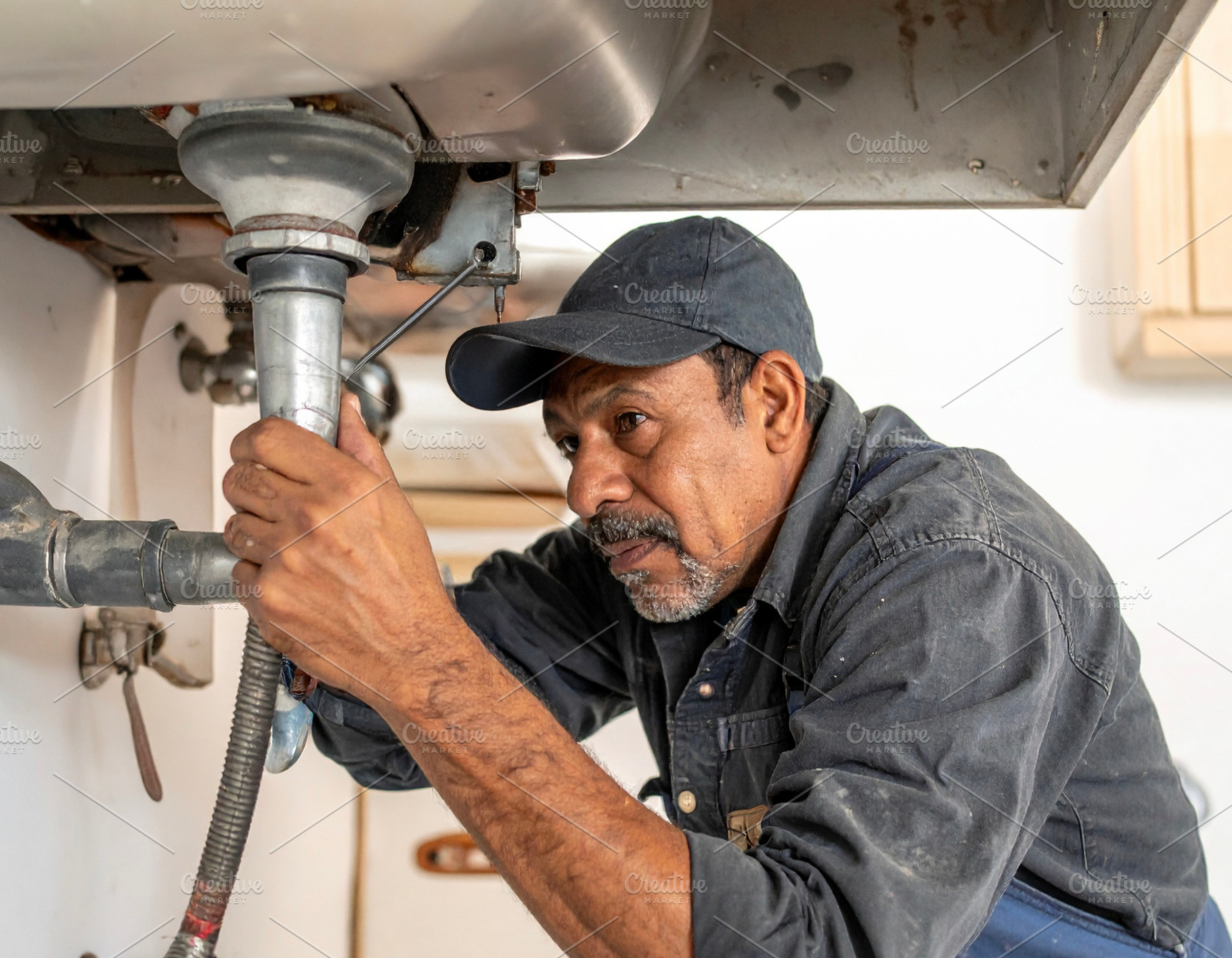 Man plumber fixing pipes under a sink., an Industrial Photo by DanFLCreativo