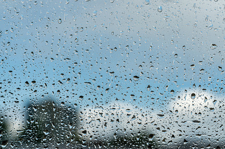 Raindrops on a window with a blue cloudy sky in the background., an Abstract Photo by Eugene_Photo