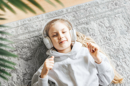 Little girl listening music lying on the floor, a Person Photo by Olena Rudo