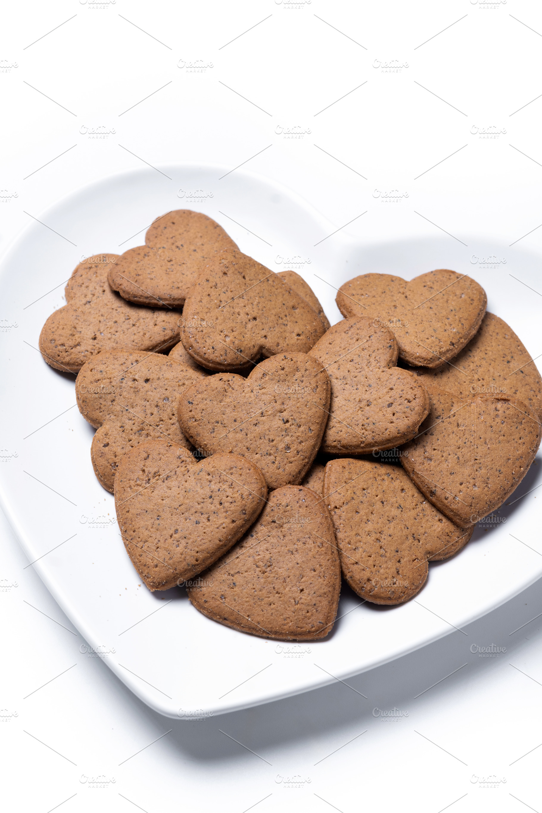 Heart-shaped gingerbread cookies on a white heart-shaped plate isolated on whit, a Food & Drink Photo by etorres69