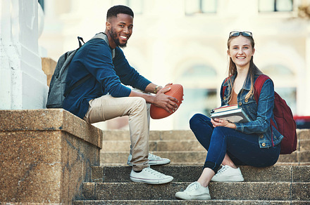 Education, campus friends and diversity students relax before college lecture class, learning or study course. University, knowledge and school portrait of woman and black man on football scholarship, a Photo by Peopleimages.com