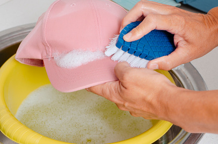 man is washing a pink cap using a brush, a Photo by Nito