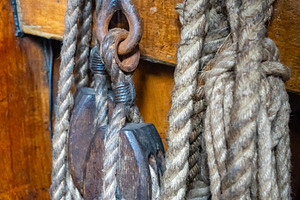 Old sailing ship ropes and wooden pulleys on a historic vessel, an Abstract Photo by GoodGoods