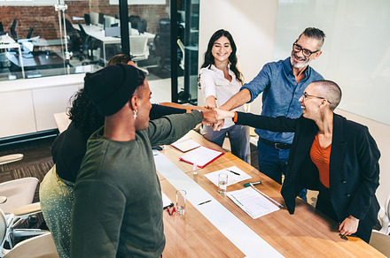Confident group of businesspeople bringing their fists together, a Person Photo by Jacob Lund
