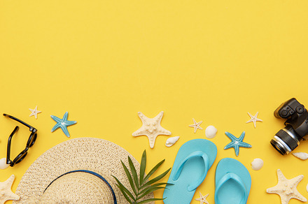 Summer holiday accessories lying on vibrant yellow background wi