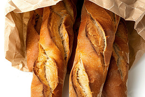 Freshly baked baguette in paper bag isolated on white background, a Food & Drink Photo by AlyaAnd