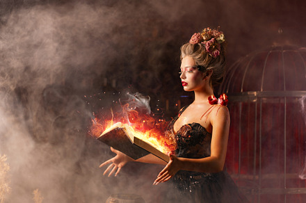 Young witch with glowing book of spell in dark smoky room, a Person Photo by andreonegin market