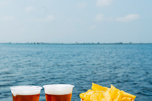 cups with beer and some potato chips on a dock, a Photo by Nito