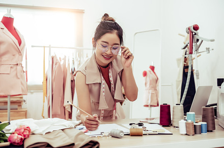Attractive Asian female fashion designer working in home office, a Beauty & Fashion Photo by Ministocker