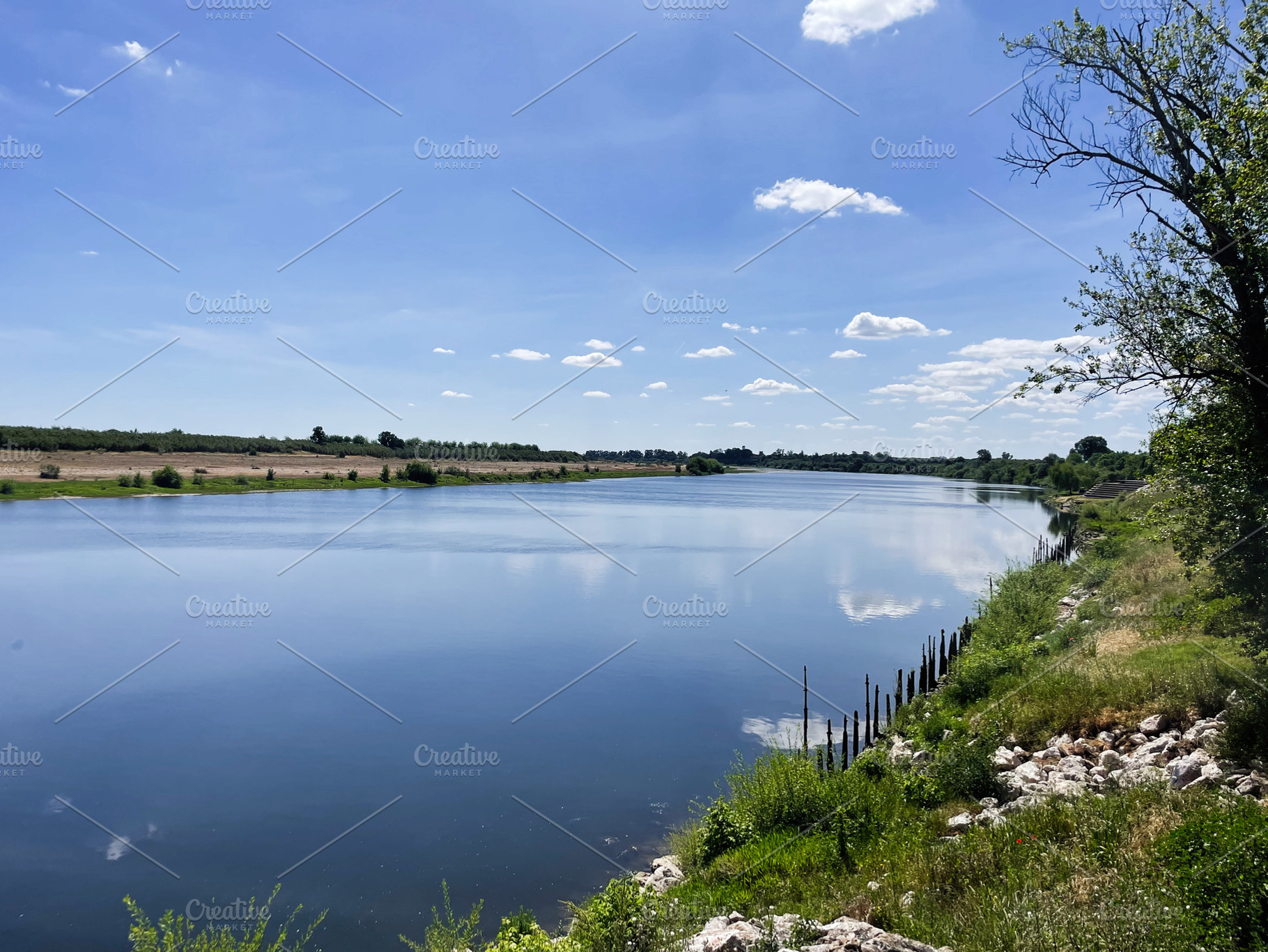 Beautiful riverside landscape on a clear day with blue sky and greenery, a Photo by AS photostudio