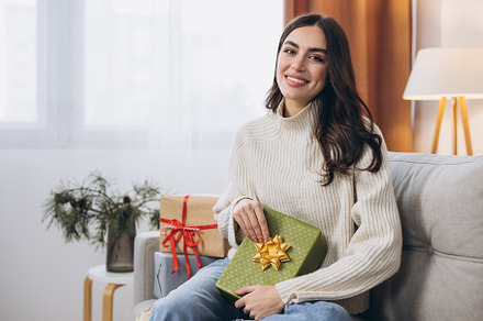 Beautiful happy woman unwrapping New Year or Christmas presents