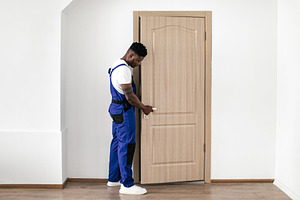 Black Repairman Installing Entry Door, Fixing Lock And Handle Indoor, a Photo by Prostock-Studio