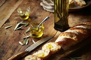 Extra virgin olive oil bottle and olives on a rustic wooden tabl, a Photo by Studio ANNA