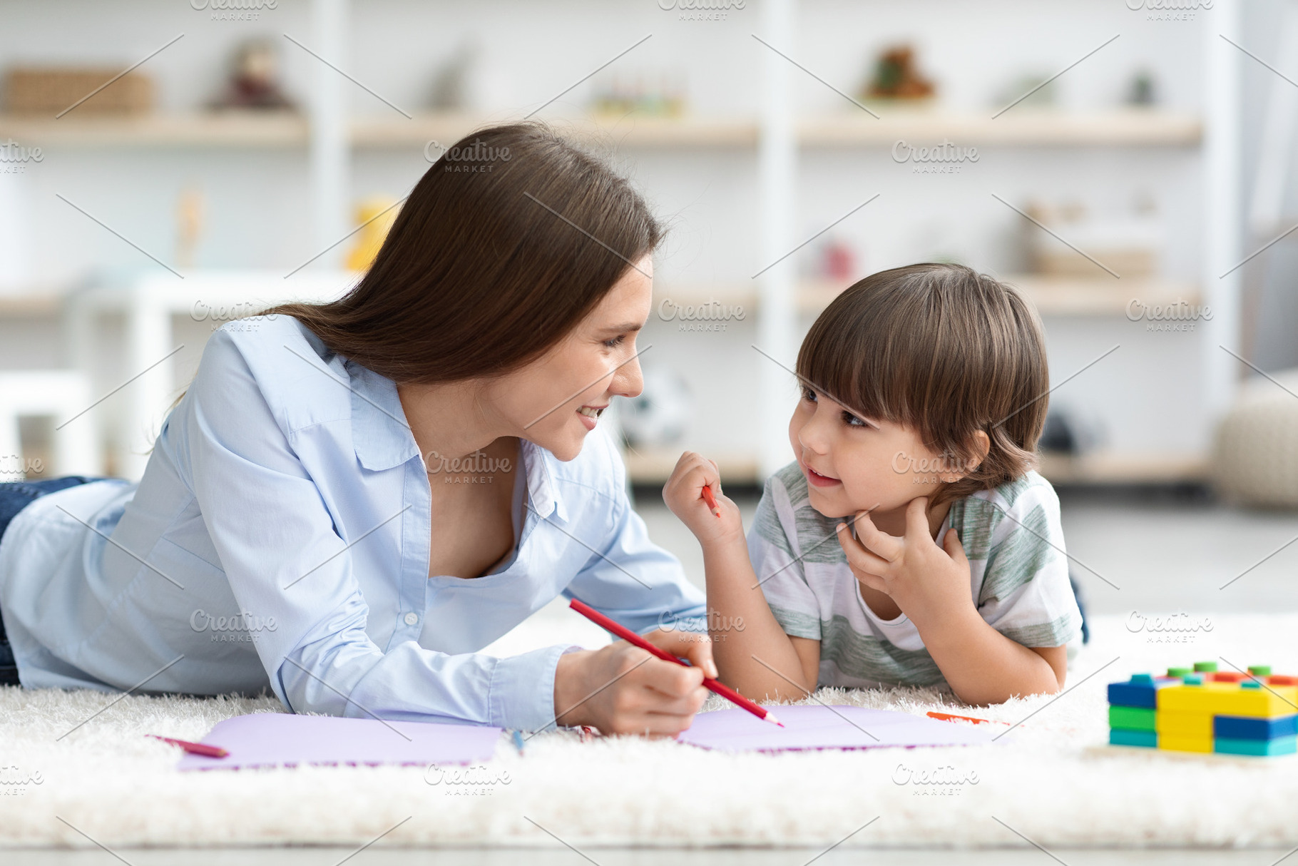 Carefree domestic pastime. Happy little boy drawing together with teacher, lyin, a Photo by Prostock-Studio