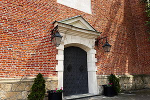 Ornate metal door and brick entrance with lanterns and planters