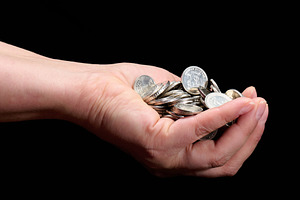Hand holding a pile of silver coins on a black background, a Business Photo by ndanko
