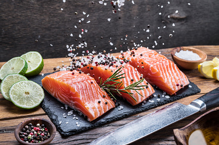 Fresh salmon fillets on black cuttin featuring basil, black, and chilli pepper, a Food & Drink Photo by Volff
