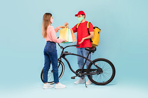 Deliveryman Giving Bags To Woman Delivering Parcel On Blue Background, a Photo by Prostock-Studio